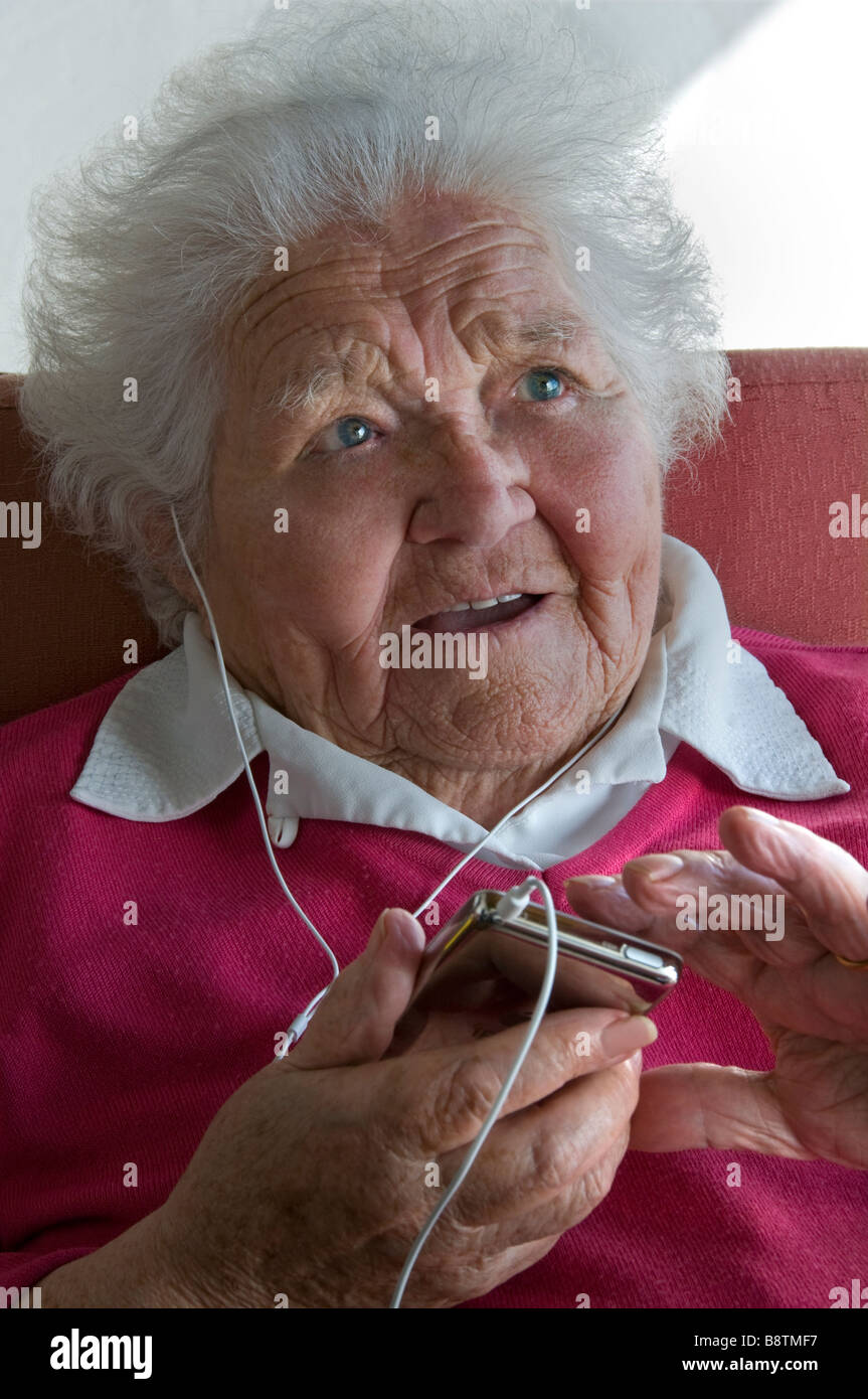 Ältere Dame iPOD AUDIO BUCH MUSIK PLAYER LERNEN SPRACHE OHRHÖRER ältere Dame mit Ihrem tragbaren Player für eine Vielzahl von digitalen Audio Media Dateien Stockfoto