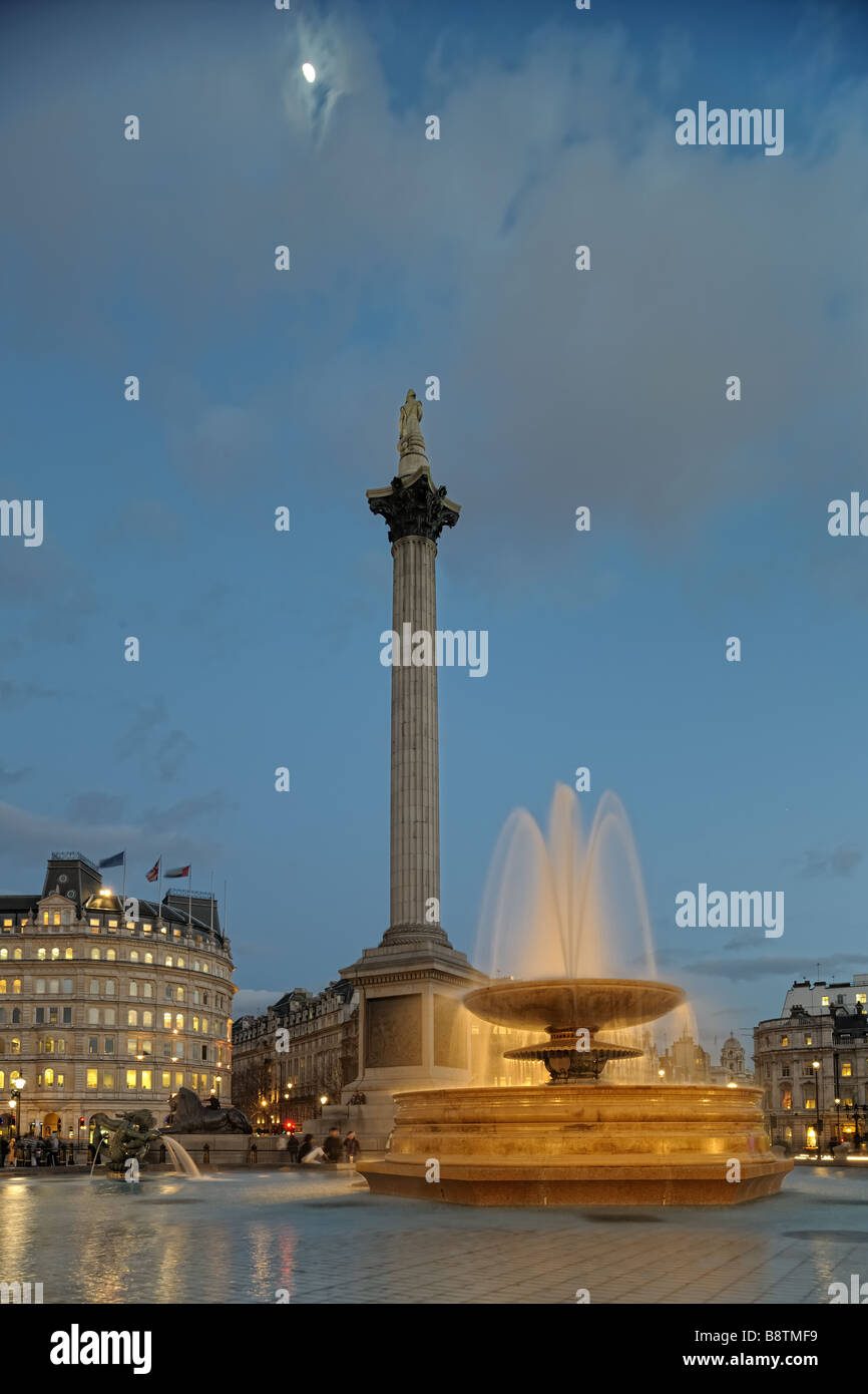 Trafalgar Square-Brunnen in der Abenddämmerung mit Nelson s Spalte im Hintergrund beleuchtet Stockfoto