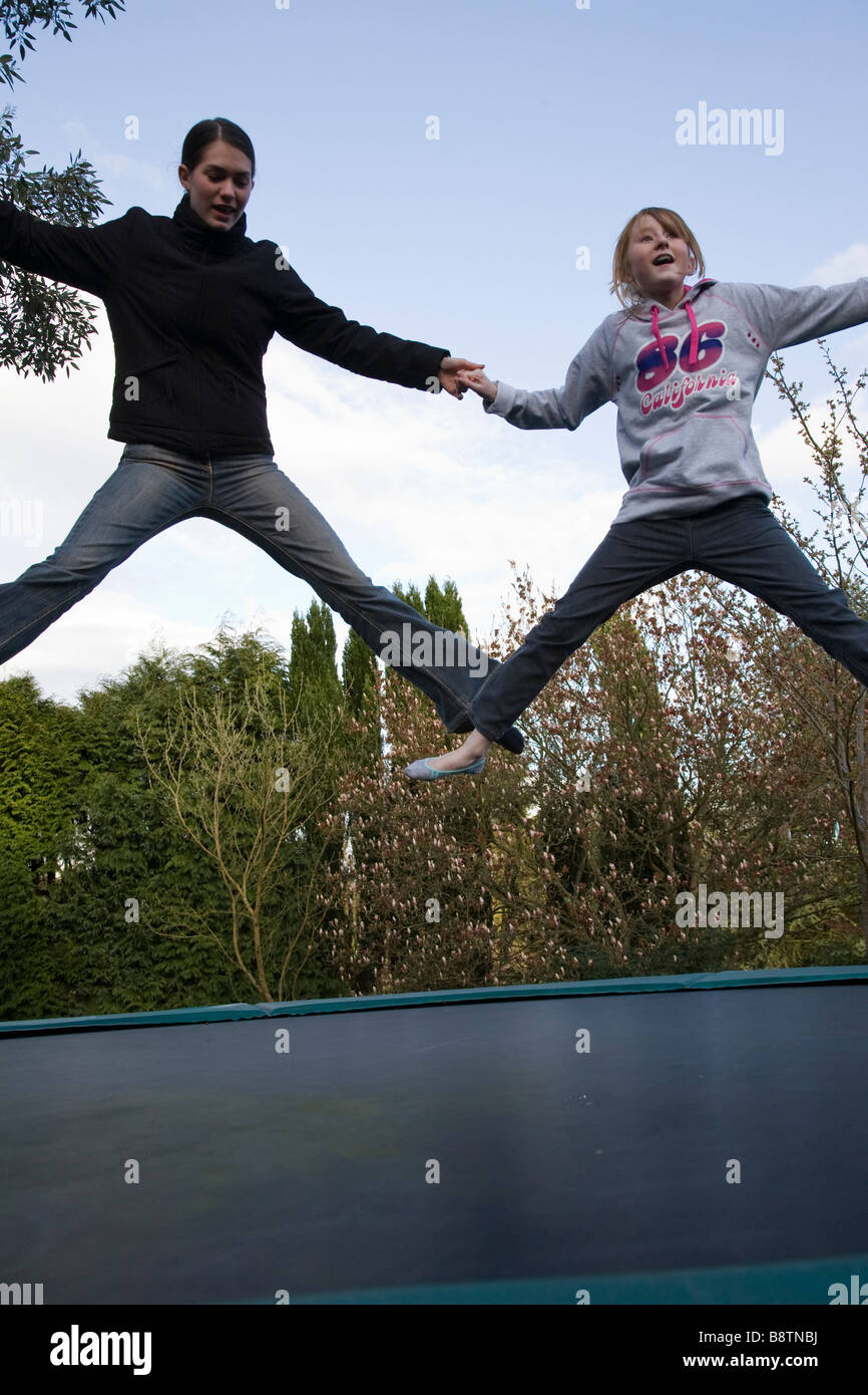 Zwei Mädchen im Teenageralter Vergnügen sich auf einem Trampolin, Surrey, England. Stockfoto