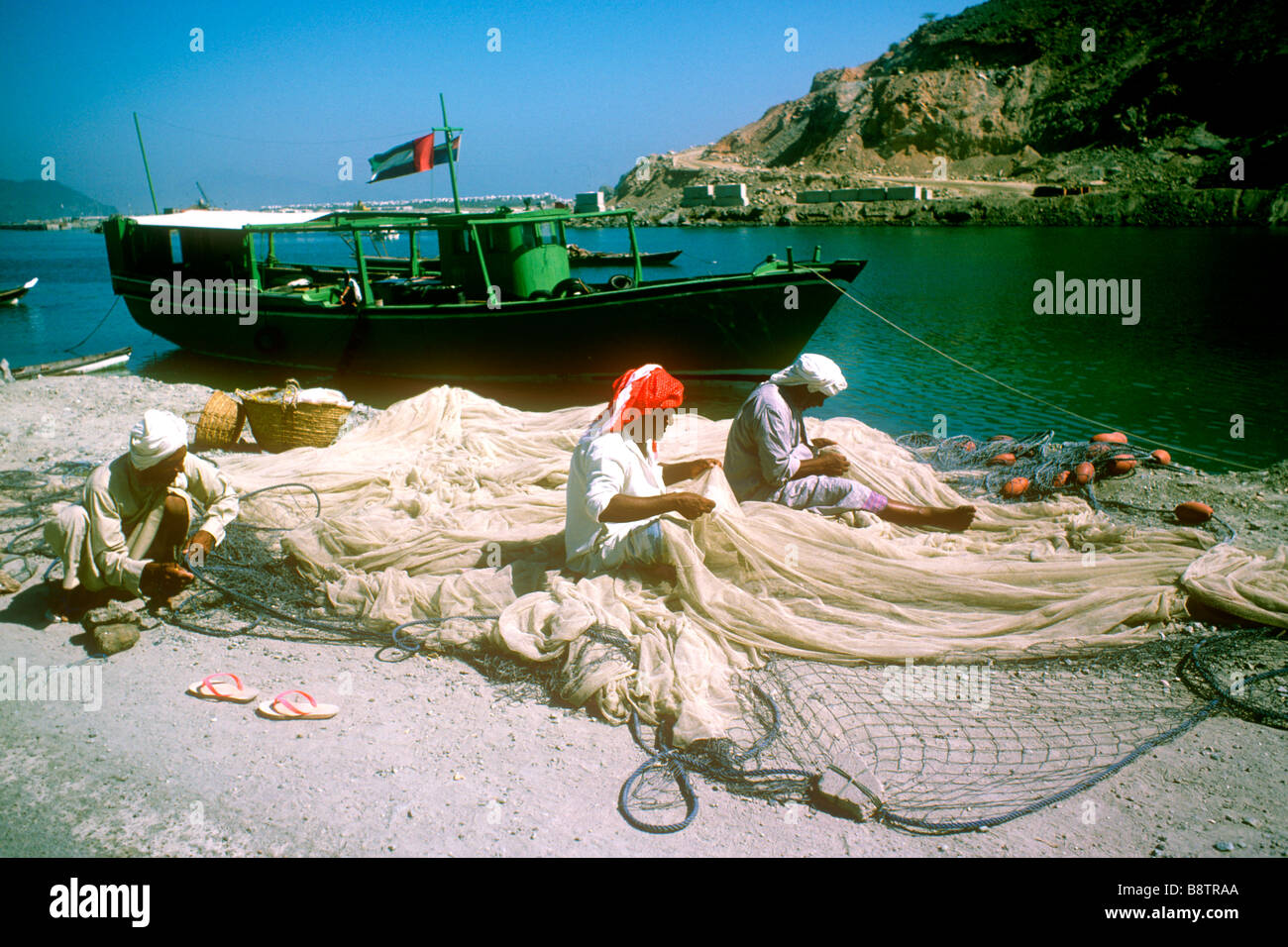 Alten Gulf Coast Tage Khor Fakkan Fischer ausbessern Netze mit ihren Boot Sharjah Arabische Meer Szene Vereinigte Arabische Emirate Stockfoto