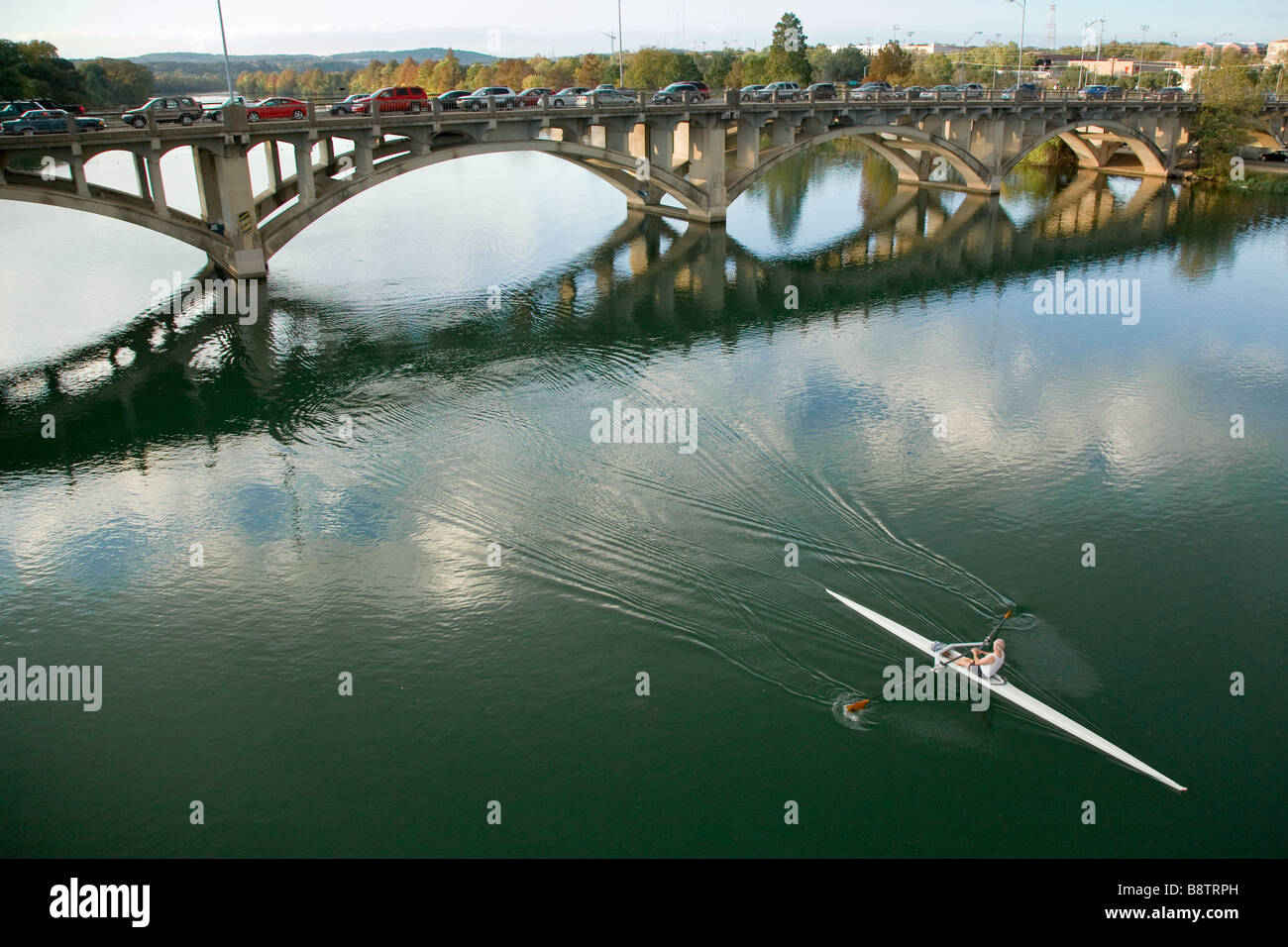 Ein Ruderer schwimmt vorbei an der der Lamar Street Bridge auf Lady Bird Lake (Stadtsee) in Austin, Texas Stockfoto
