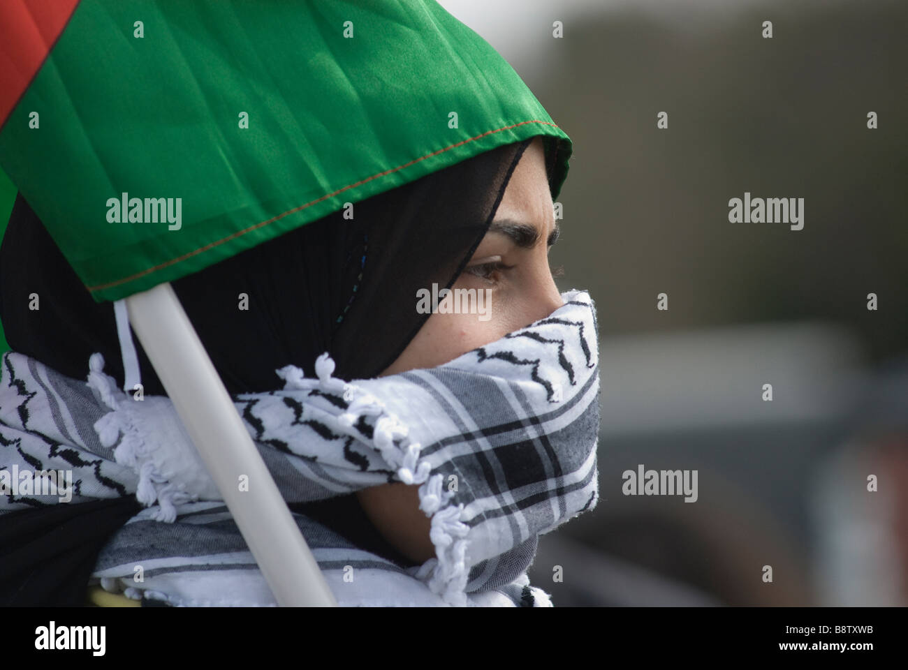 Die junge palästinensische Frau bedeckt ihr Gesicht während eines Protests im Westjordanland mit einem traditionellen schwarz-weißen Fischnetzmuster Keffiyeh oder kufiya-Schal Stockfoto