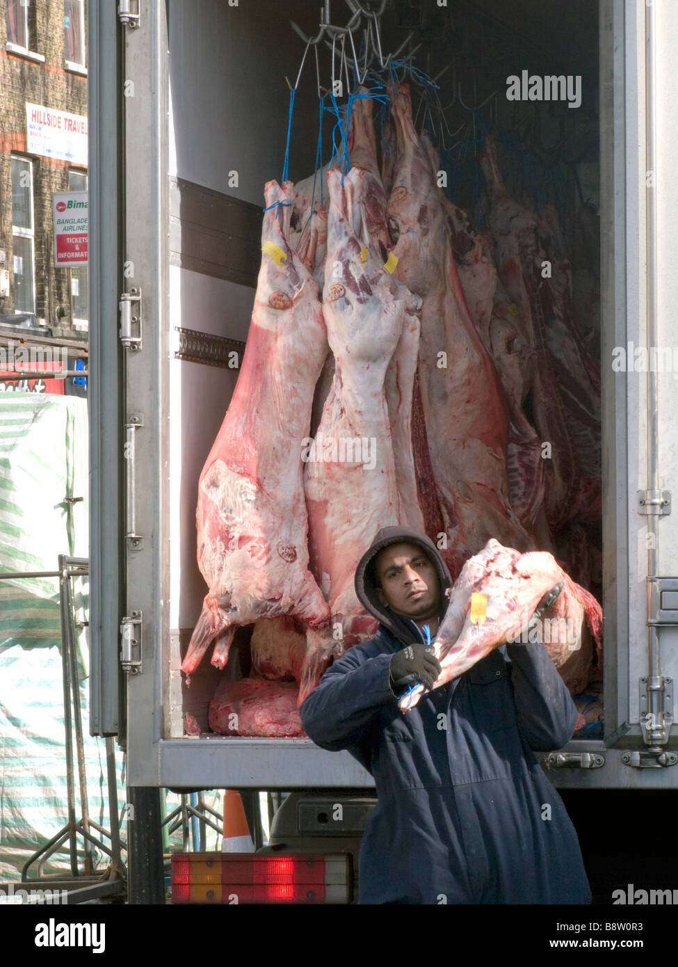 VEREINIGTES KÖNIGREICH. Porter tragen ein Halal-Lamm zu einem Muslim Metzger in Whitechapel Markt, Osten London.Photo von Julio Etchart Stockfoto