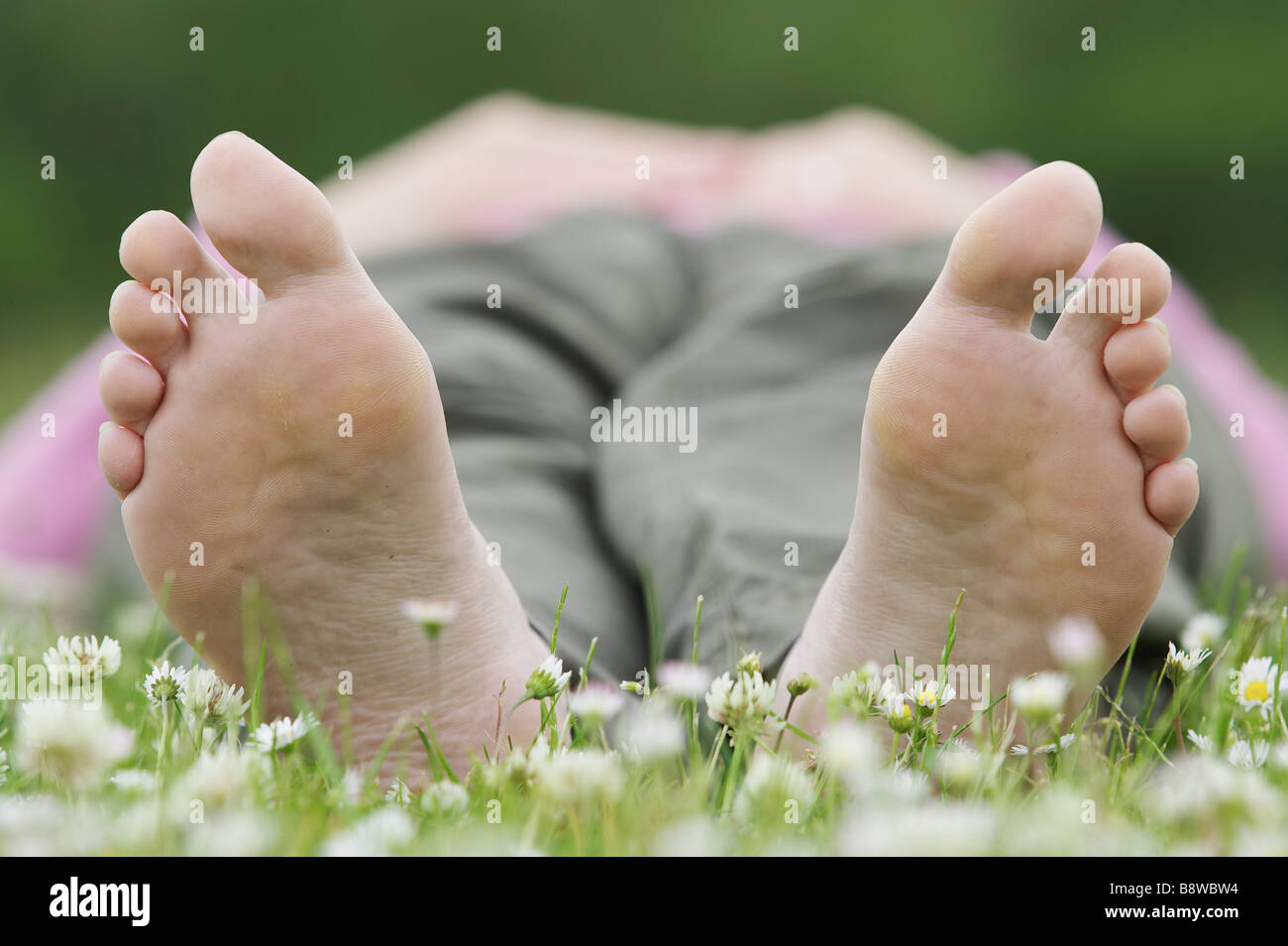 Nahaufnahme von Unterseiten der nackten Füße der Frau liegt auf dem Rasen Stockfoto