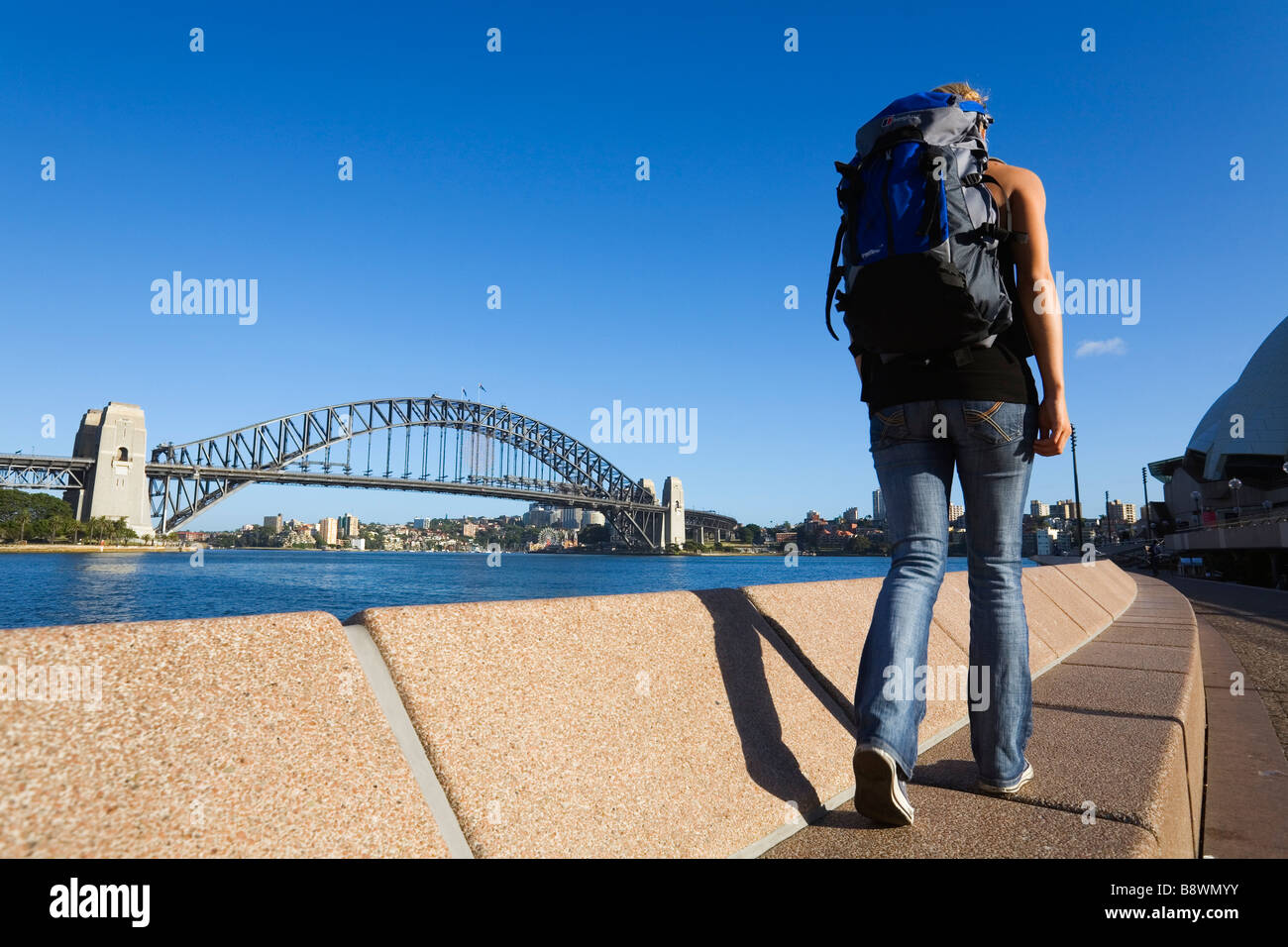 Eine Backpacker Spaziergänge entlang des Ufers Sydney Hafen.  Sydney, New South Wales, Australien Stockfoto