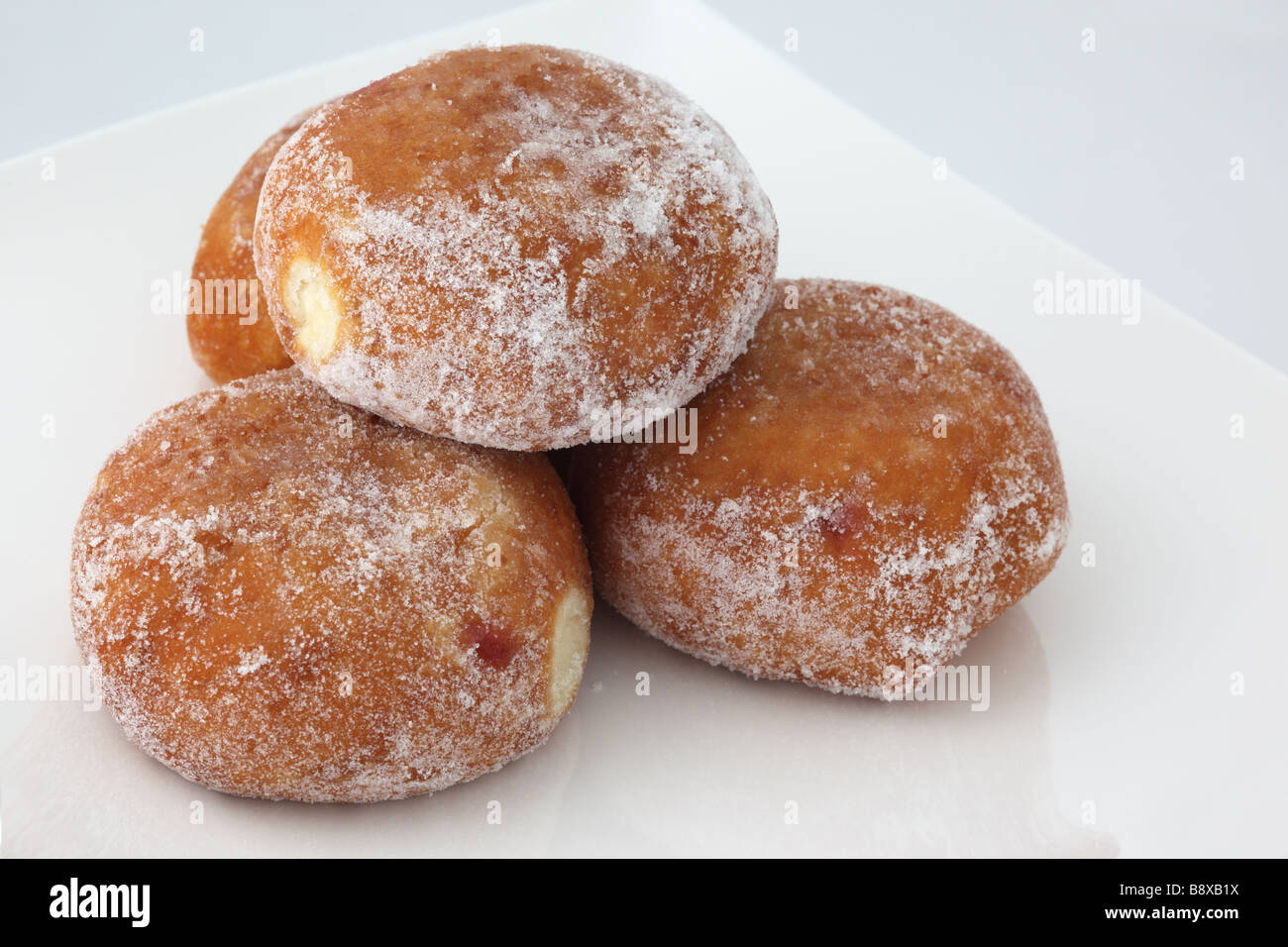 Nahaufnahme von vier frisch gezuckerten Konfitüren Donuts gegen ein Weißer Hintergrund Stockfoto
