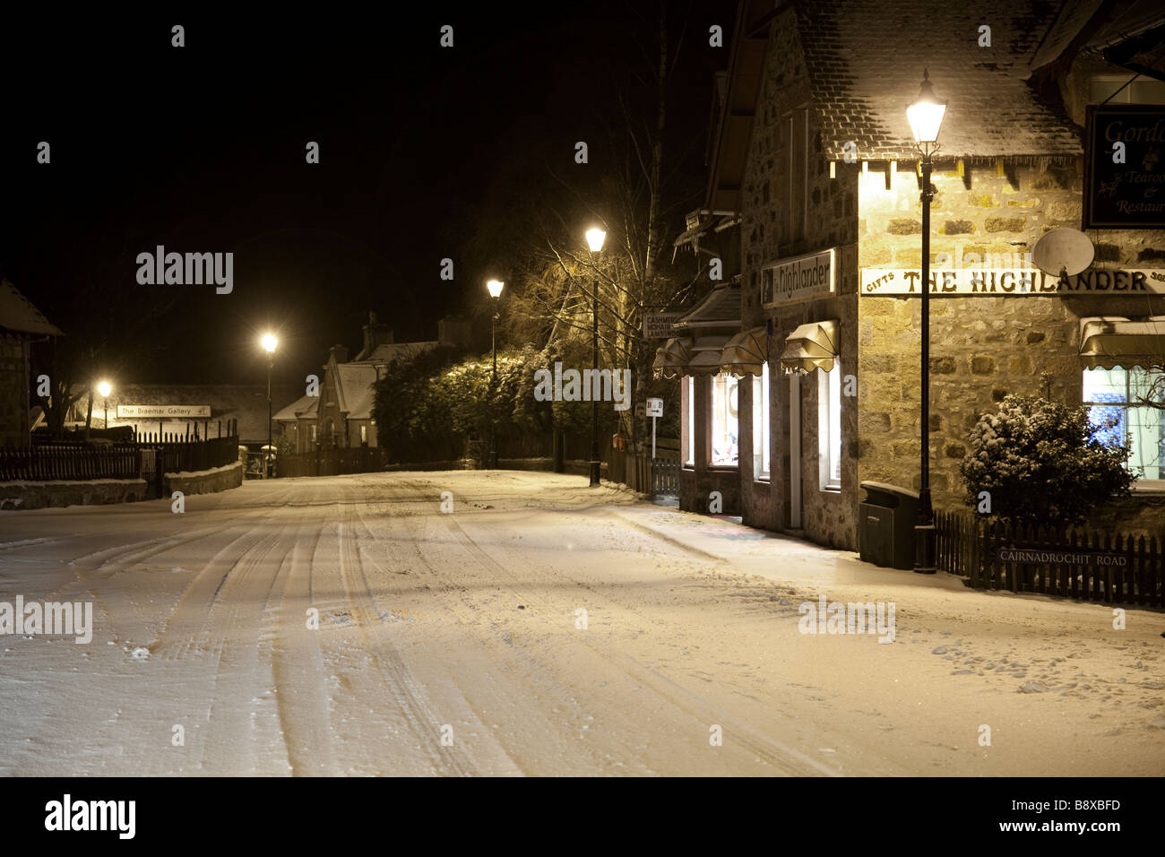 Die Häuser und Geschäfte auf einem Schnee Winter Nacht im abgelegenen Hochland Braemar Village, Aberdeenshire, Schottland, Großbritannien Stockfoto