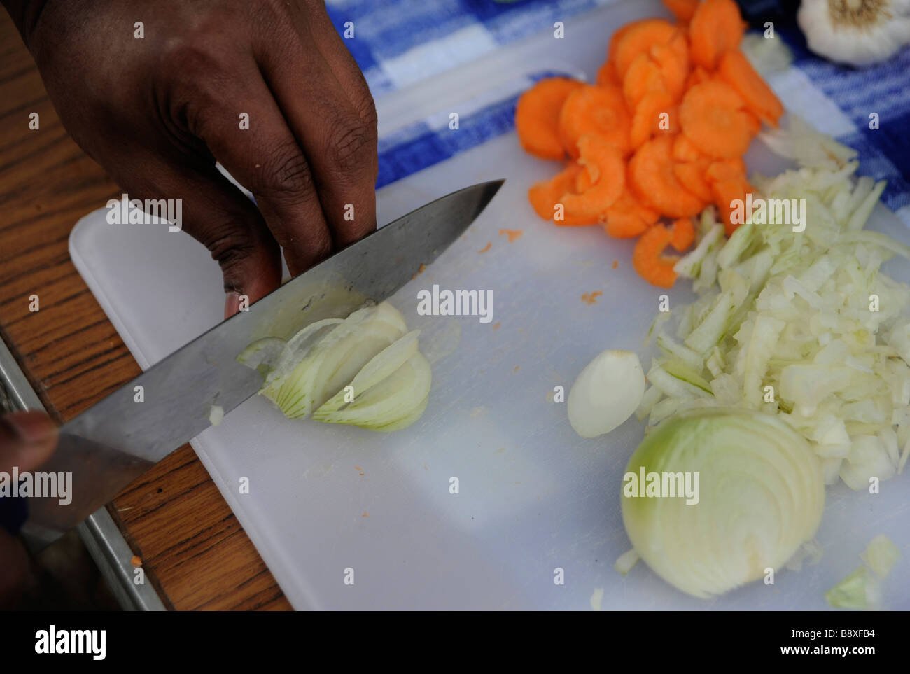 Eine Zwiebel in Scheiben geschnitten mit einem Messer in der Vorbereitung für ein Gemüse-Curry. Stockfoto