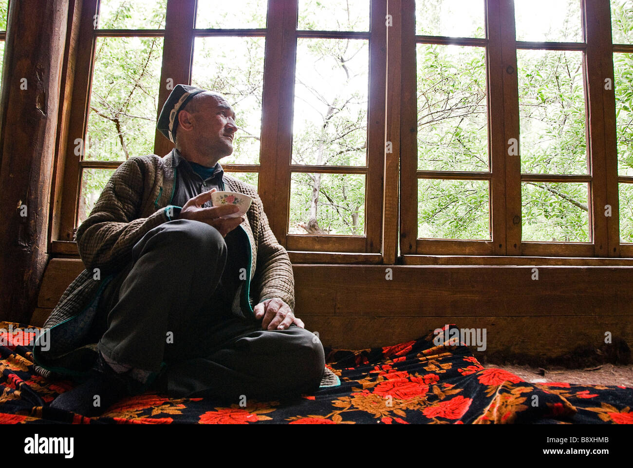 Erwachsenen Kleid in traditioneller Kleidung, Tee zu trinken, in der Nähe eines Fensters, Tadschikistan Stockfoto