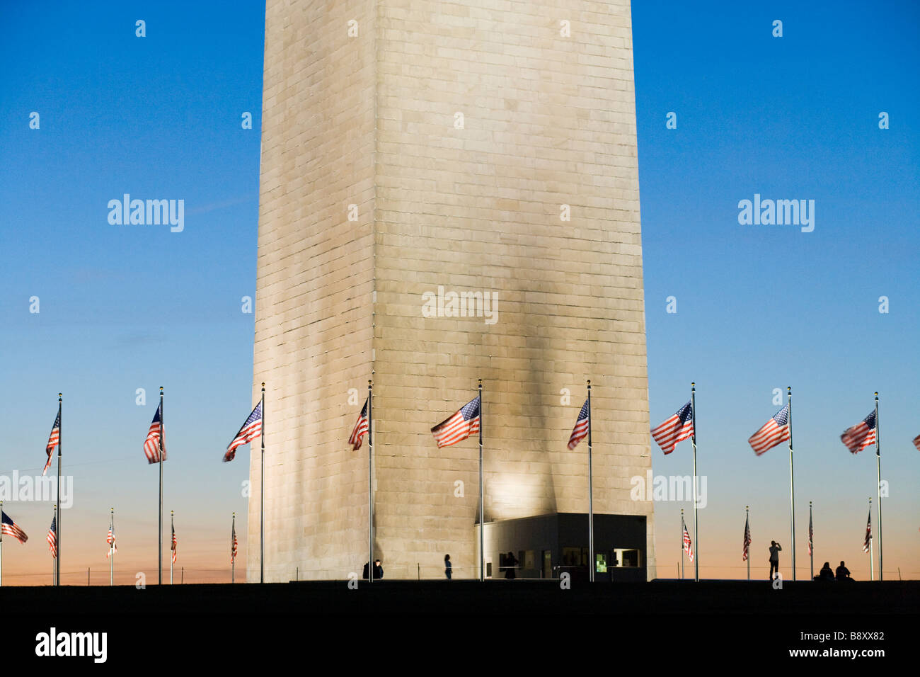Die Basis des Washington Monuments mit amerikanischen Fahnen und Besucher bei Sonnenuntergang. Washington DC USA. Stockfoto