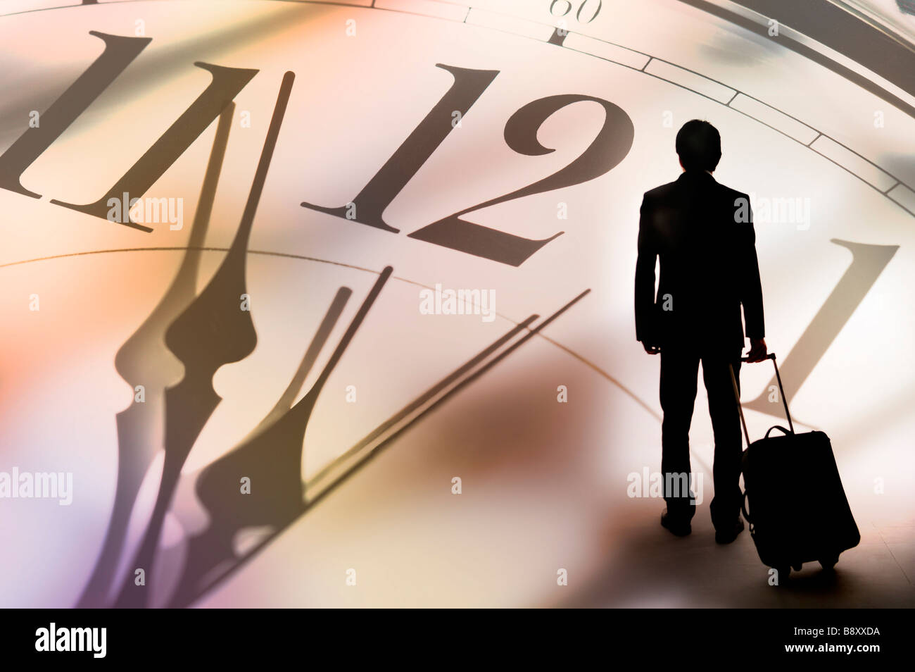 Silhouette eines Mannes hält einen Koffer im Hintergrund eine große Uhr Stockfoto