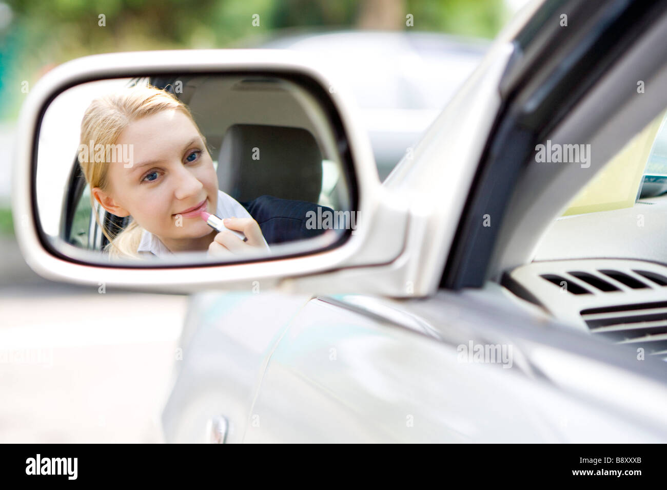 Junge Frau beim Schminken aus dem Spiegel des Autos Stockfoto