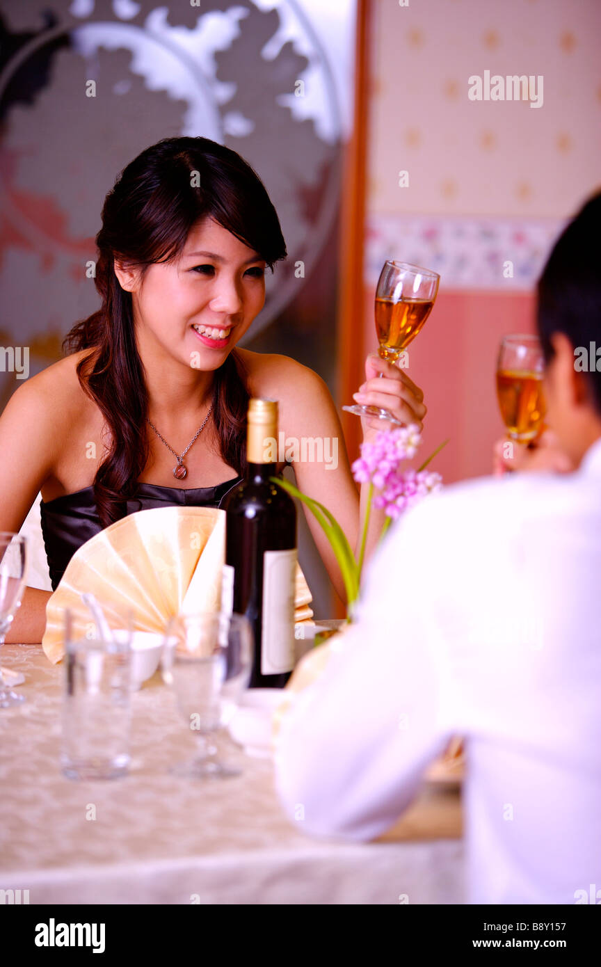 Mann und Frau sitzen neben dem Tisch und hält ein Glas Wein Stockfoto