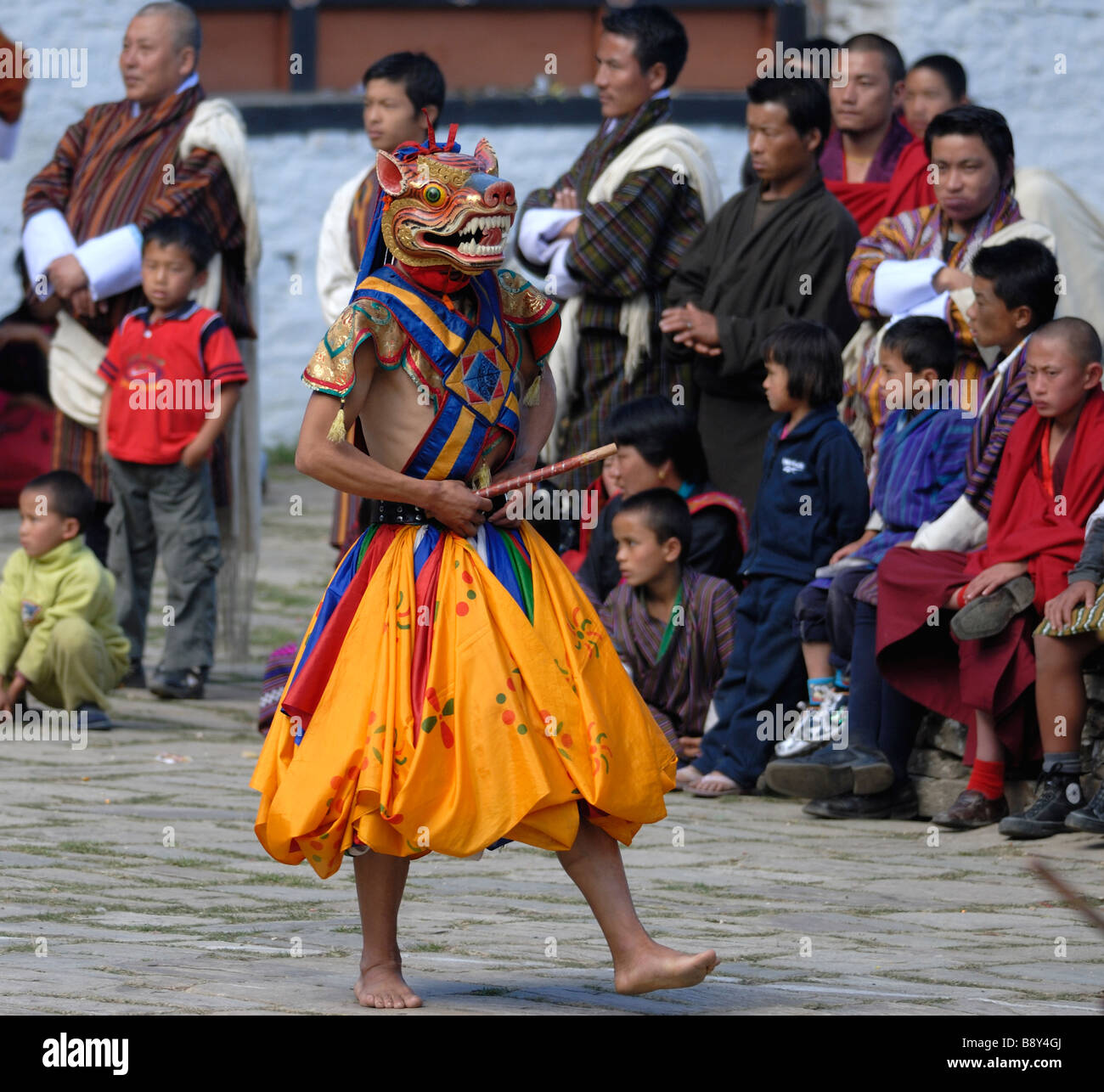 Tänzerin in bunten Kleid und bemalten Tiermaske im Hof des Mongar Dzong Stockfoto