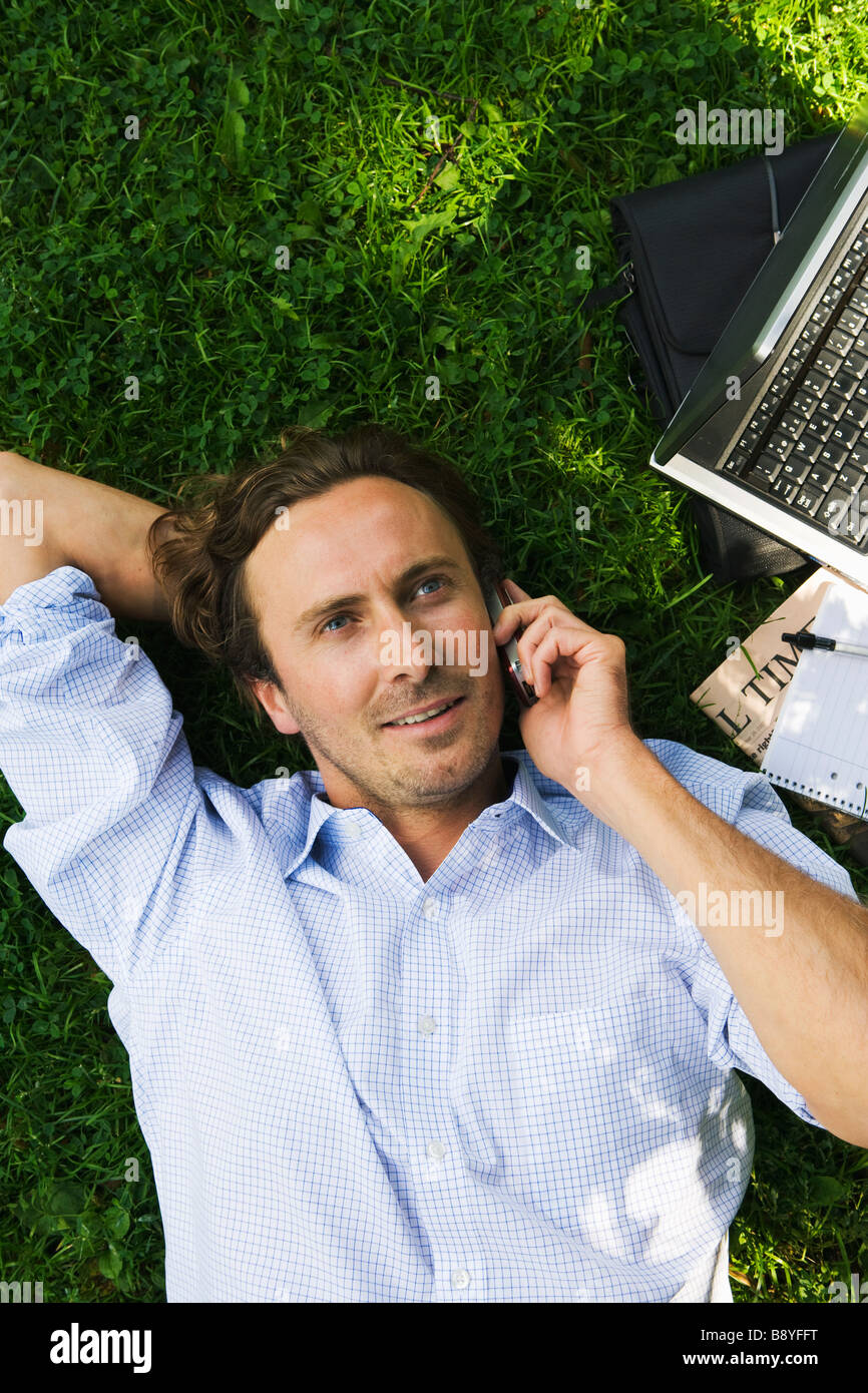 Ein Geschäftsmann mit einem Handy in einem Park Schweden. Stockfoto