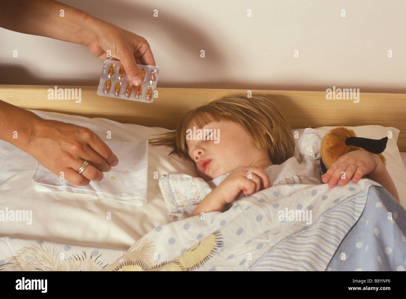Mutter ein Kind s Kissen, ihr in der Nacht mit ihren kalten atmen zu helfen eine Öl-Kapsel aufsetzen Stockfoto