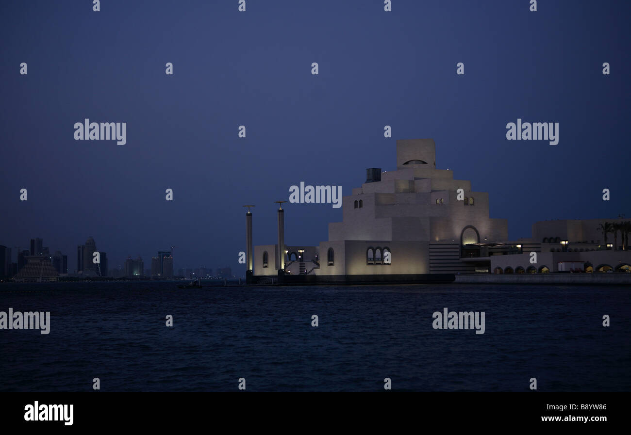 Das Museum für islamische Kunst in Doha Katar in der Abenddämmerung mit den Gebäuden des Landkreises New noch sichtbar über die Bucht Stockfoto
