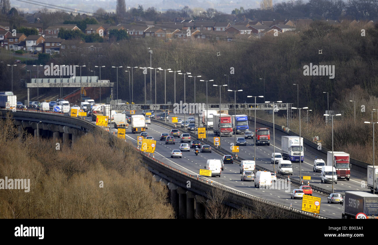 EINEN ERHÖHTEN ABSCHNITT DES M6 AUTOBAHN IN DER NÄHE VON BIRMINGHAM UK MIT WOHNHÄUSERN IN DER NÄHE. Stockfoto