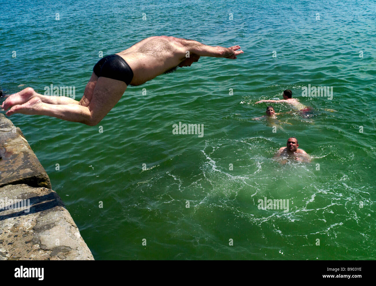 Ein Mann taucht ins Meer und die Badegäste genießen Sie die Sommersonne am Strand in Acadia Odessa Ukraine Stockfoto