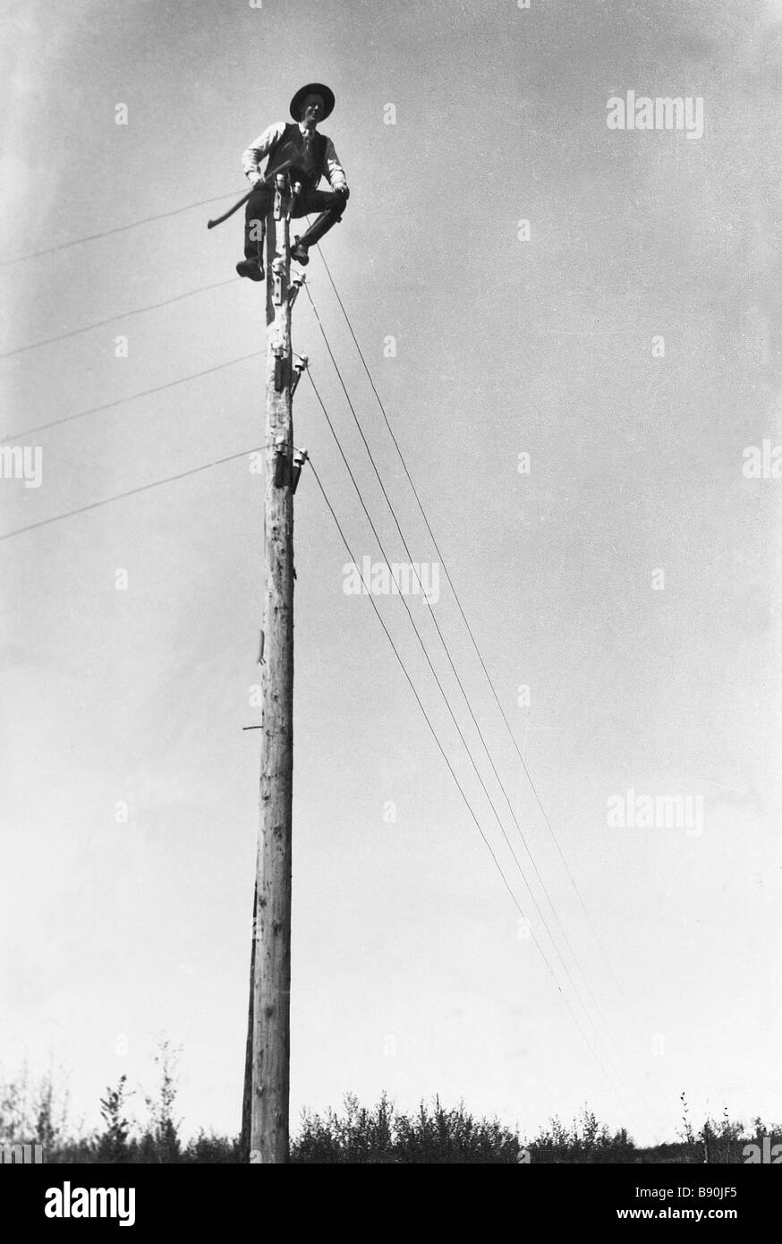 FL3240, AHNEN FOTO; Mann sitzt Op Telegrafenmast Stockfoto