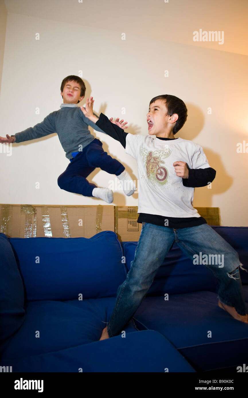 Ältere männliche Kind Abwehr eine Kung-Fu-Attacke von seinem jüngeren Bruder während des inländischen Spiels kämpfen auf dem sofa Stockfoto