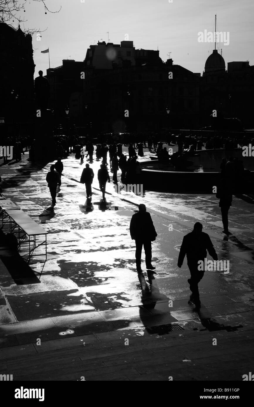 Touristen, die Silhouette durch die niedrige Wintersonne am Trafalgar Square in London Stockfoto