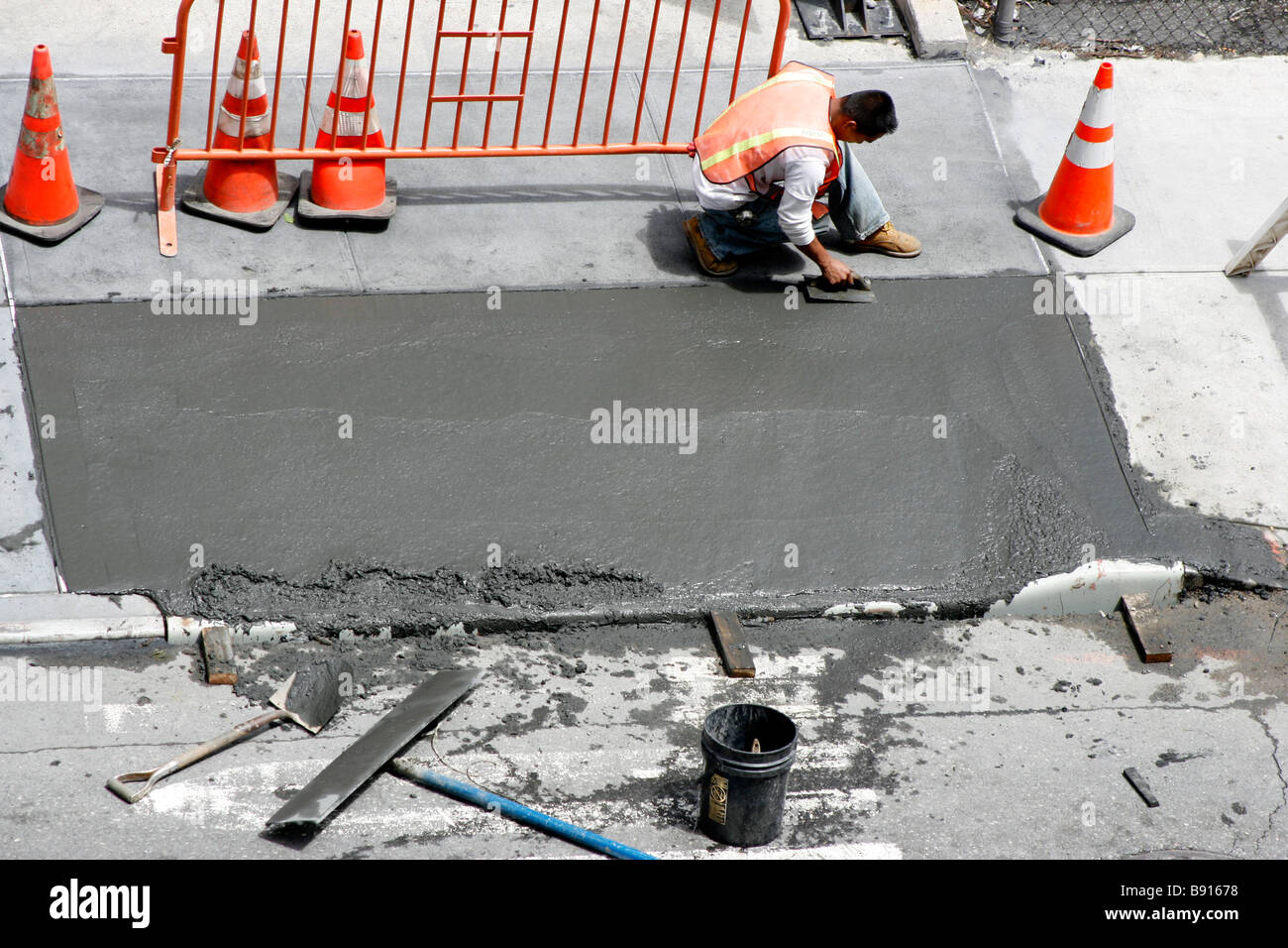 Mann einen frisch gezapftes nassen Beton Gehweg Glättung. Stockfoto