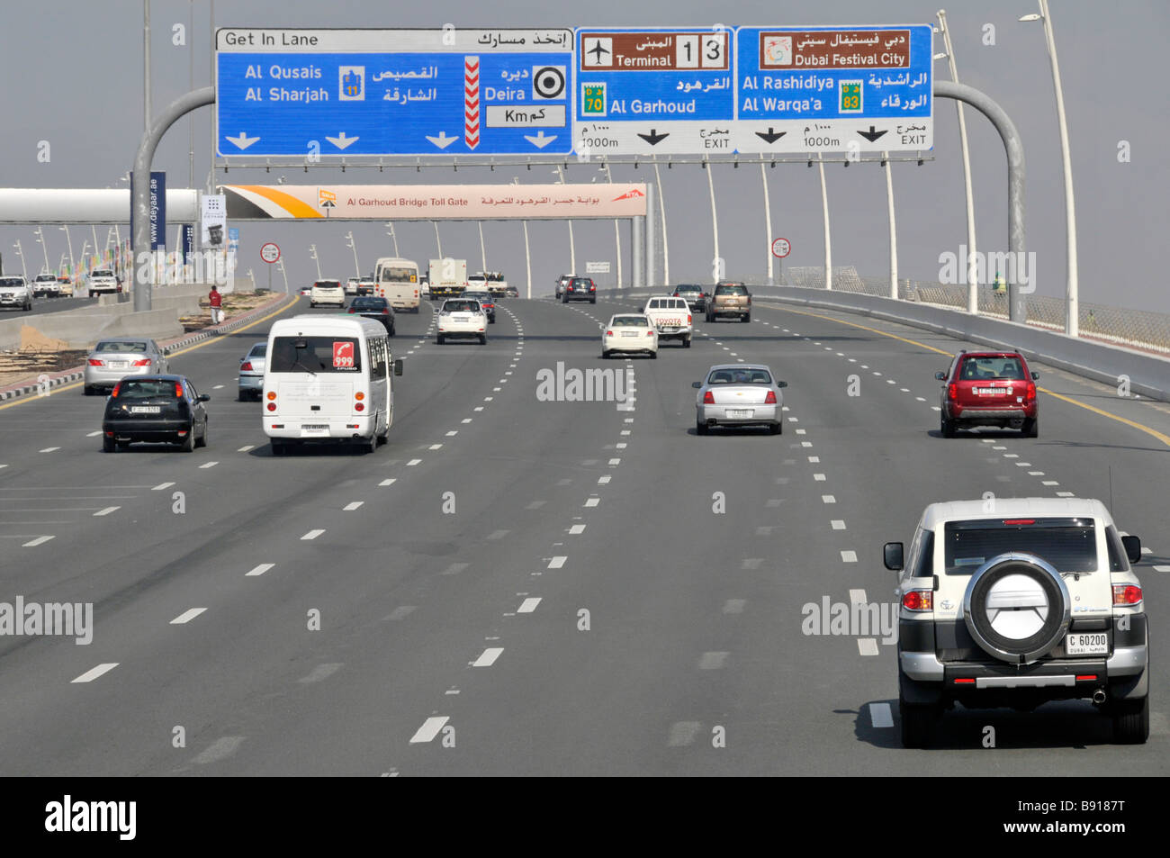 Dubai Autoverkehr auf modernen siebenspurigen Autobahn Autobahn zweisprachig Wegweiser für die Gantry-Ausfahrt zu den Flughafenterminals 1 und 4 United Arabische Emirate VAE Naher Osten Stockfoto