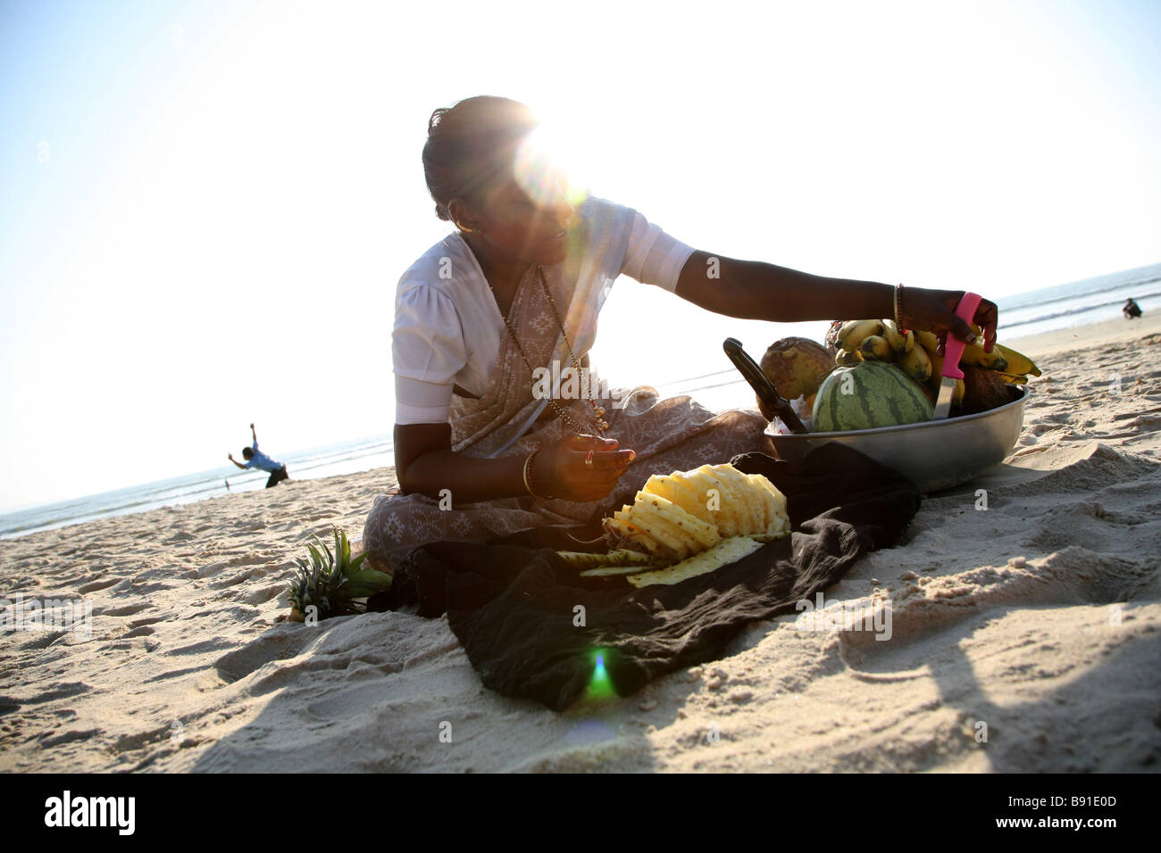 Eine lokale Frau Sellign frischen tropischen Früchten für Touristen auf Mobor Beach in Goa, Indien. Stockfoto