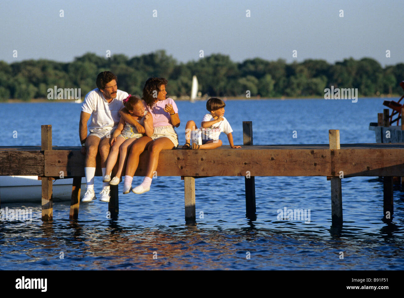 FAMILIE SITZT AM STEG AM SEE HARRIET, EINER BELIEBTEN INNERSTÄDTISCHEN SEE UND PARK IN MINNEAPOLIS, MINNESOTA.  SOMMER. Stockfoto