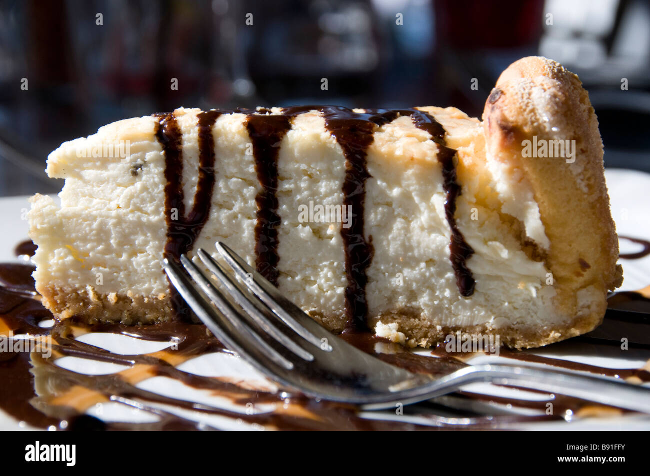 Stück Käsekuchen auf Teller mit Schokoladensirup Stockfoto