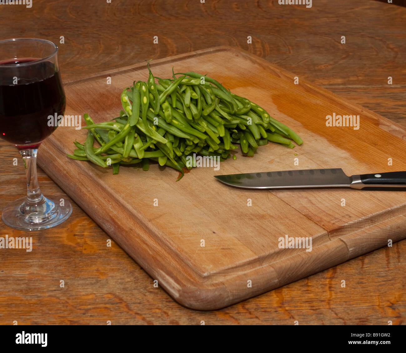 Ein Schneidebrett mit Jullienned grüne Bohnen, ein Santokumesser und ein Glas Wein für den chef Stockfoto