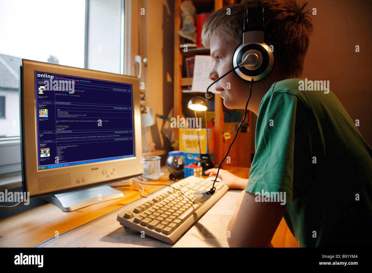 Ein Junge, 13 Jahre alt, ist in seinem Kinderzimmer und Gespräche im Chat zu einem Chat-Mitglied von Voice-over Ip. Er trägt einen Kopfhörer. Stockfoto