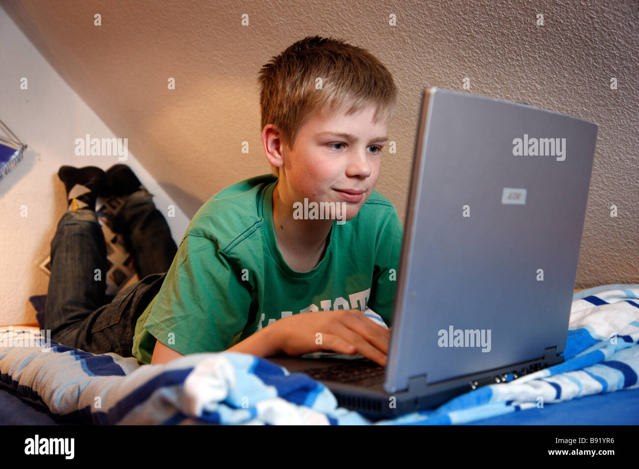 Ein Junge, 13 Jahre alt, arbeitet an seinem Laptop auf seinem Bett in