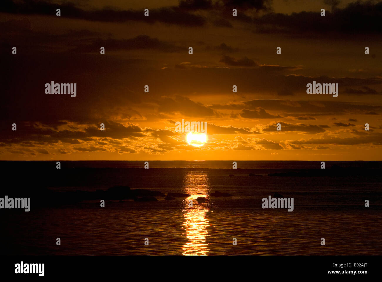 Ein Sonnenuntergang über Felsen und Riffe in Mauritius Stockfoto