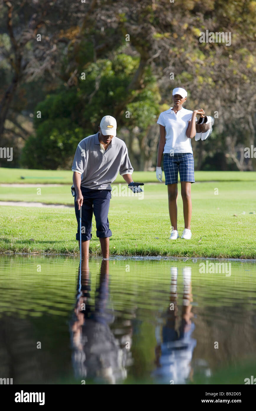 Mann auf der Suche nach Golfball im Wasserhindernis Stockfotografie - Alamy