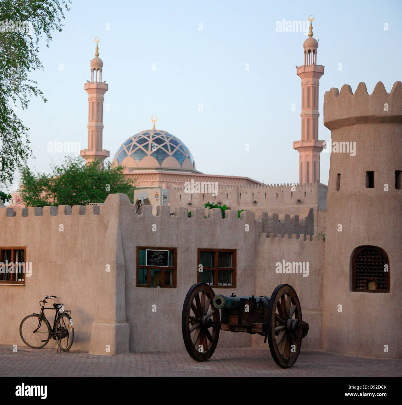 Alten Canon stehen außerhalb eines arabischen traditionell gebauten Gebäudes mit einer Moschee im Hintergrund Dubai Vereinigte Arabische Emirate Stockfoto