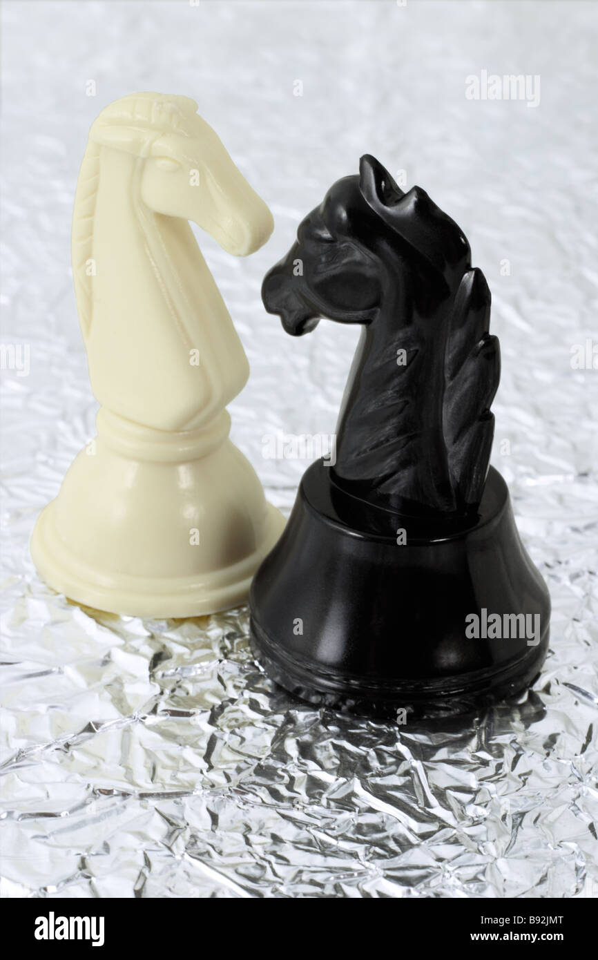 Weiße und schwarze Ritter auf metallic Silber-Muster-Hintergrund Stockfoto