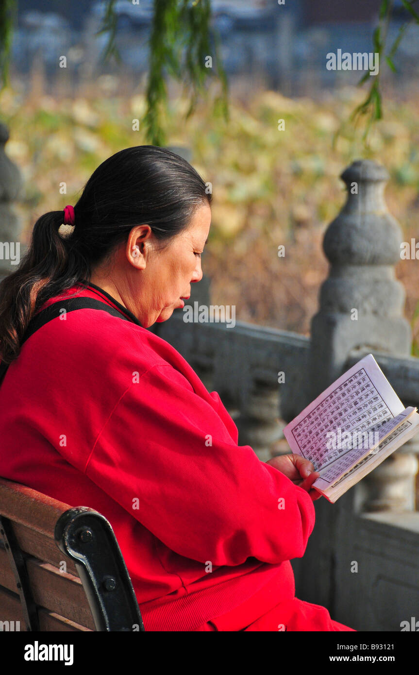 Frau liest auf einer Bank im Beihai-Park Peking China Stockfoto