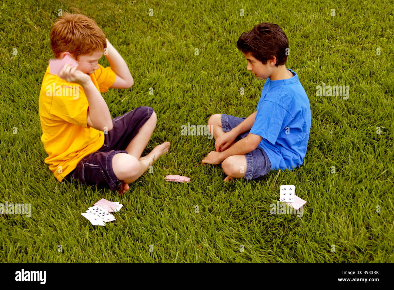 Zehn Jahre alten Jungen eine kaukasische und einem iranischen amerikanischen Karten spielen im Freien in Laguna Niguel CA Stockfoto