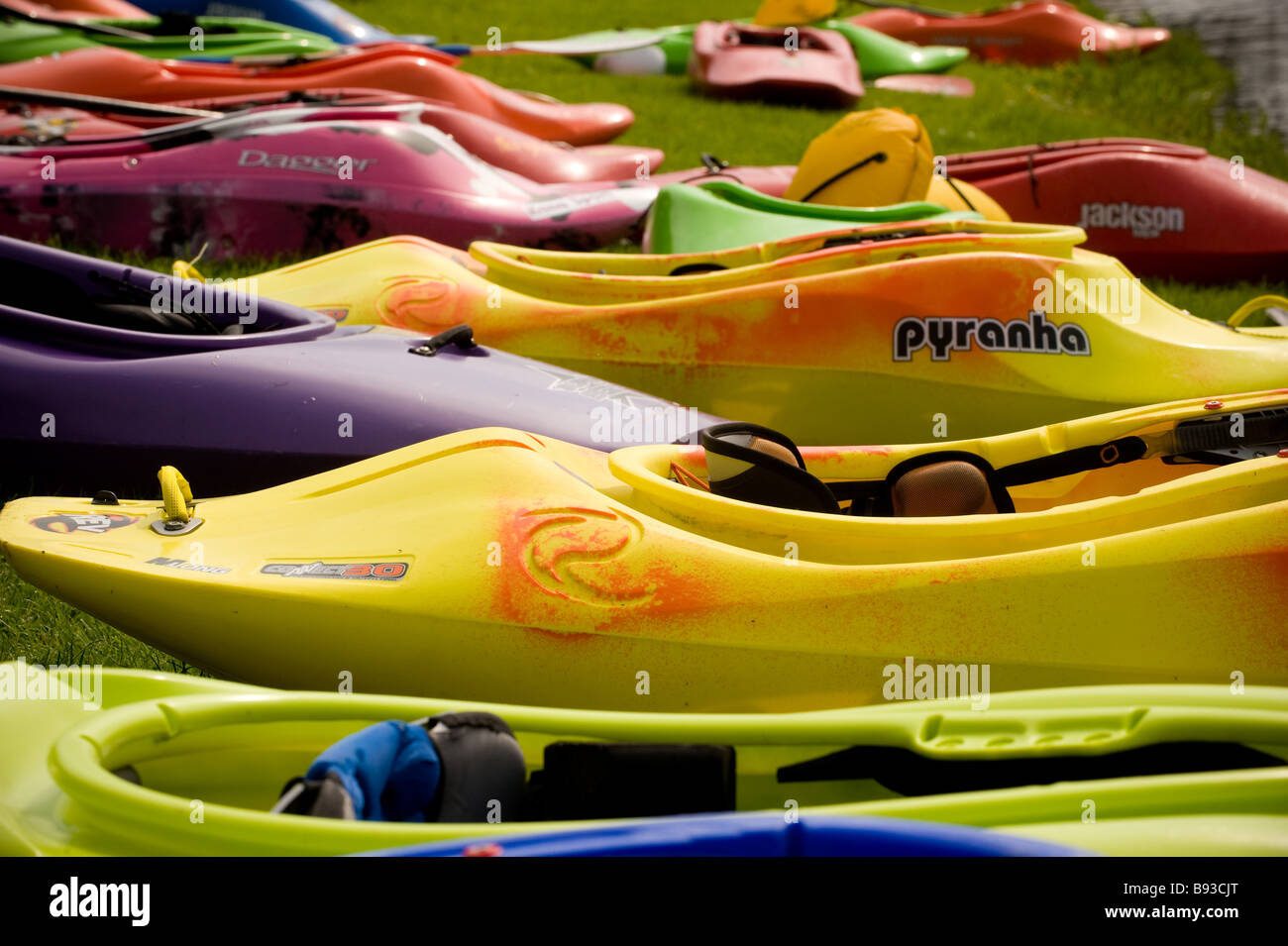 Farbenfrohe Kajaks Reihen sich am Ufer des Flusses am Tees Barrage International White Water Center mit der Tees Barrage Bridge, Großbritannien, an Stockfoto