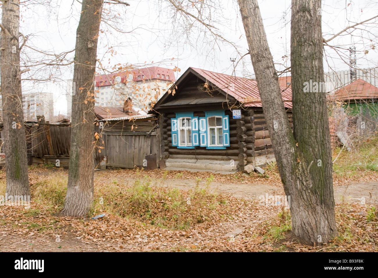 Traditionelle Holzhütte mit blauen Fensterläden vor Suburban Apartment Blocks, Jekaterinburg, Ural, Russland Stockfoto