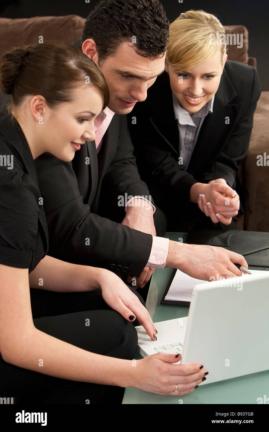 Ein Geschäftsmann und seine beiden weiblichen Kollegen eine Präsentation auf einem weißen Laptop betrachten Stockfoto