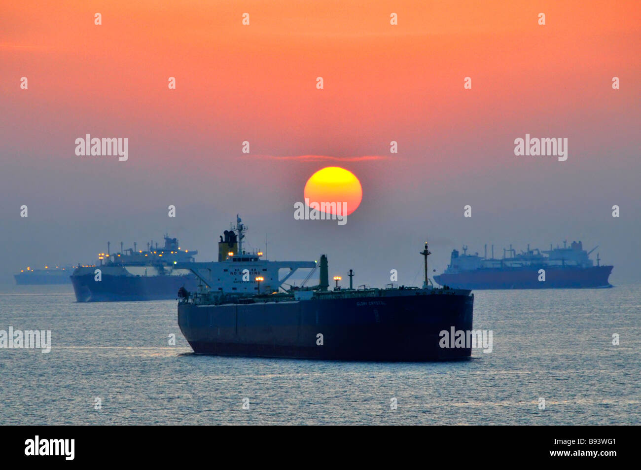 Öltanker und Massengutschiffe am Küstenankerplatz im Sonnenuntergang im unbeladenen Hafen Fujairah der Vereinigten Arabischen Emirate am Golf von Oman in der Nähe der Straße von Hormuz Stockfoto