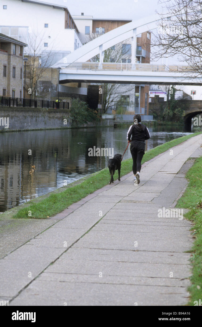 Jogger mit Hund entlang Regents Canal Stockfoto