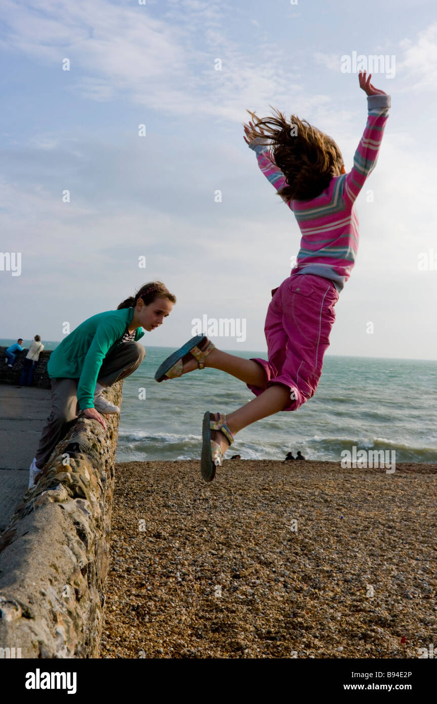 Mädchen springen auf Leiste Brighton Sussex UK Stockfoto