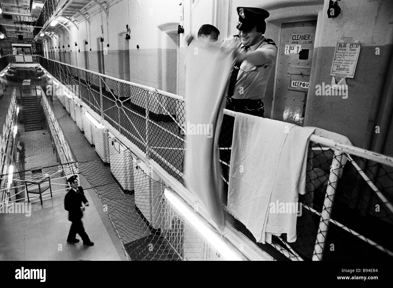 Gefängnis Offizier schüttelt Bettwäsche bei einer Durchsuchung einer der Zellen. Pentonville Prison, London, England Stockfoto