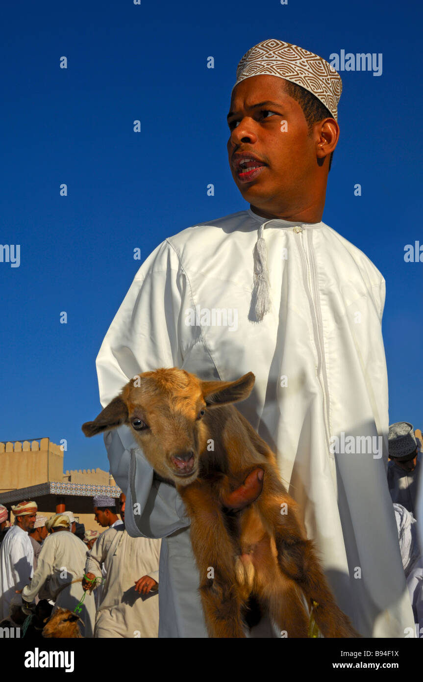 Omanische Zicklein Verkäufer in traditioneller Tracht Dishdasha auf dem Markt der Ziege von Nizwa, Sultanat von Oman Stockfoto
