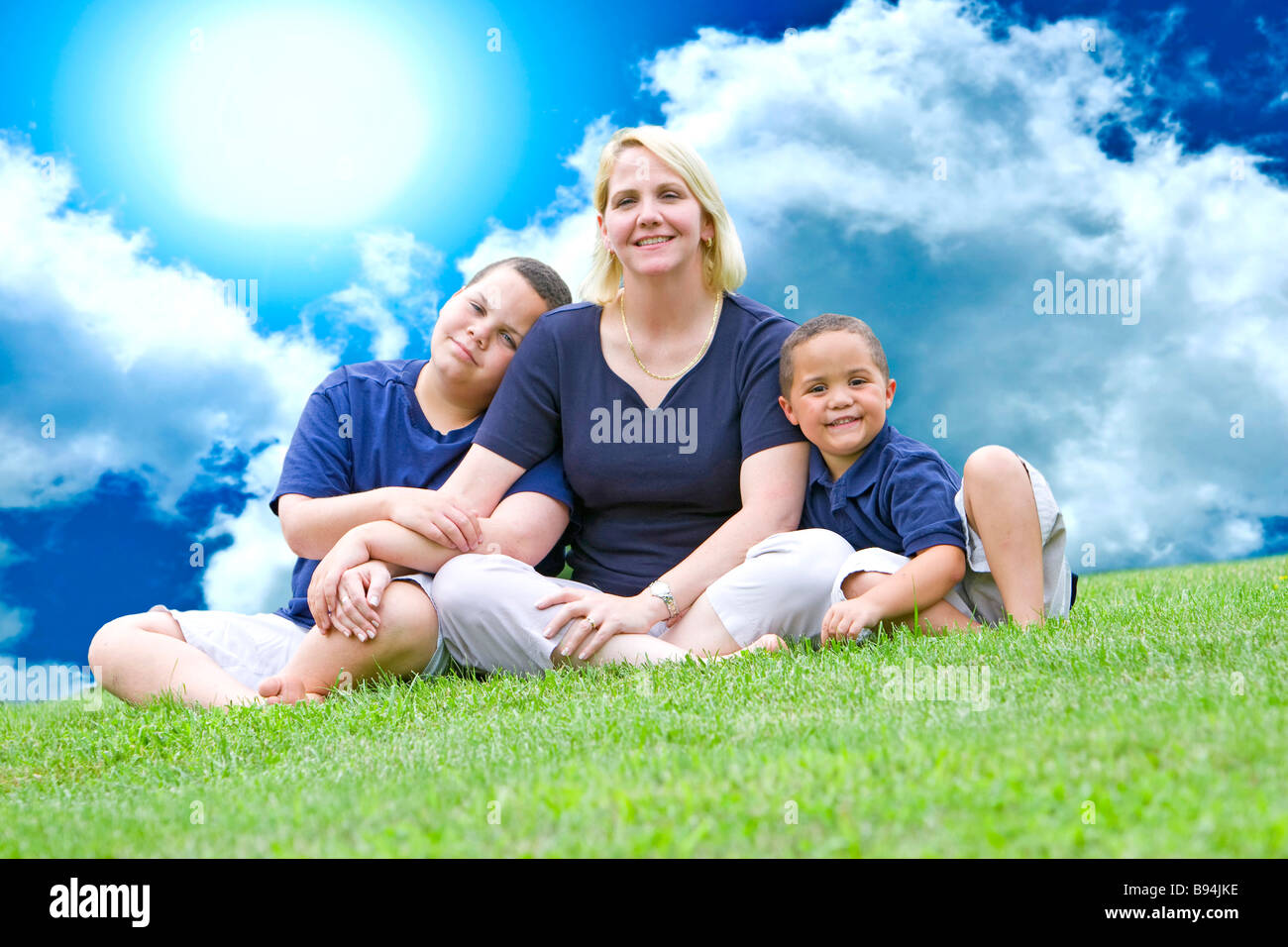 Hübsche Mutter mit ihren beiden Söhnen draußen auf dem Rasen Stockfoto