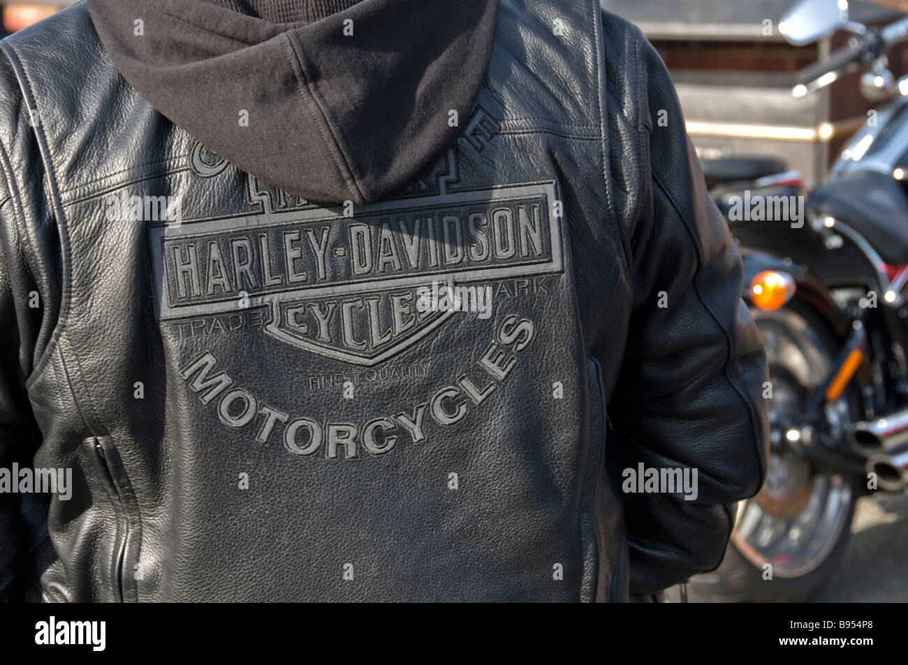 Ein Detail einer Harley-Davidson schwarze Lederjacke mit einem Harley-Davidson Motorrad in den Hintergrund, Roggen, England, UK Stockfoto